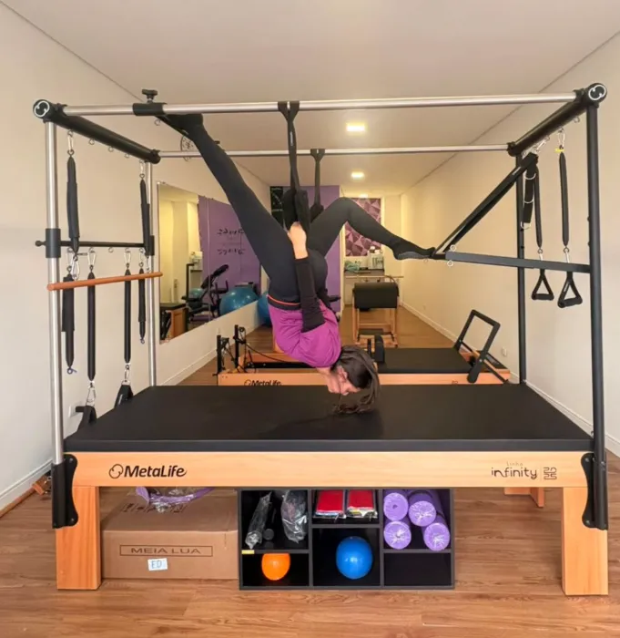 Aluna praticando exercício invertido no aparelho Cadillac no estúdio Amora Pilates